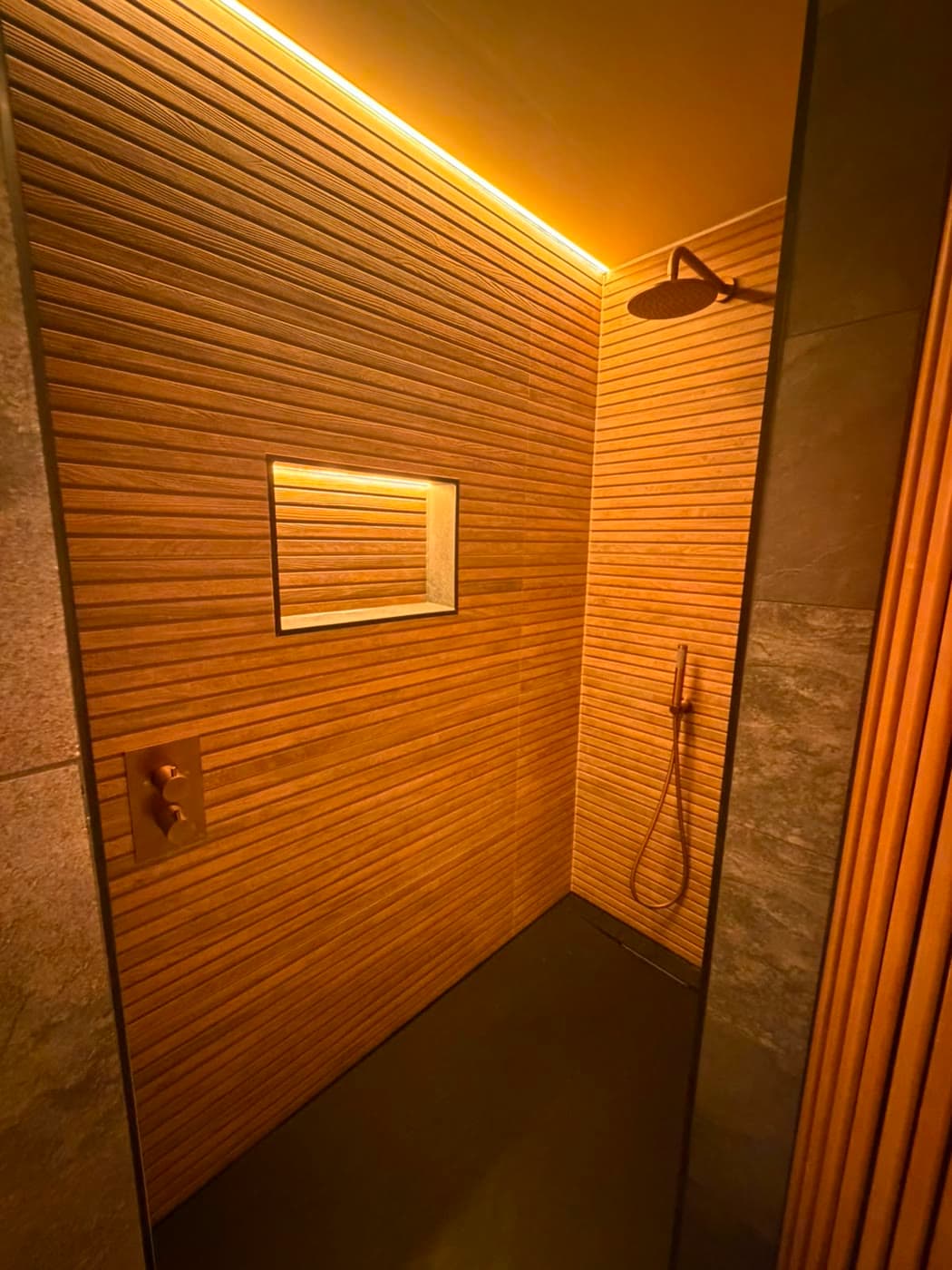 Slate tiled bathroom with a sauna cabin and slatted timber panelling, fitted by Caro Bathrooms