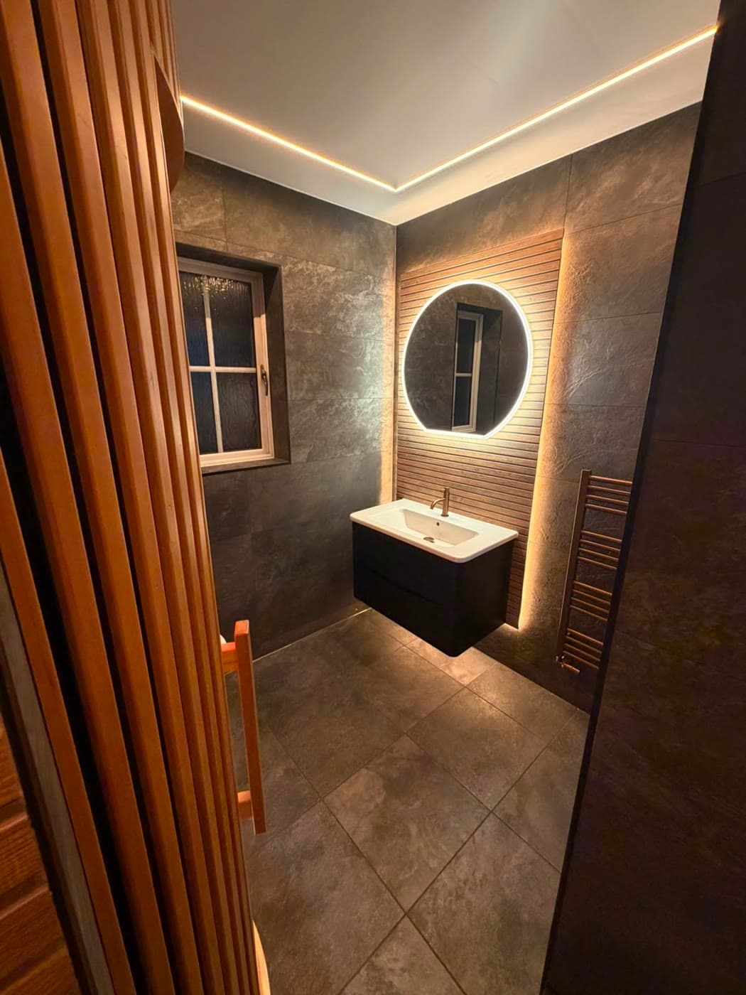 Slate tiled bathroom with a sauna cabin and slatted timber panelling, fitted by Caro Bathrooms