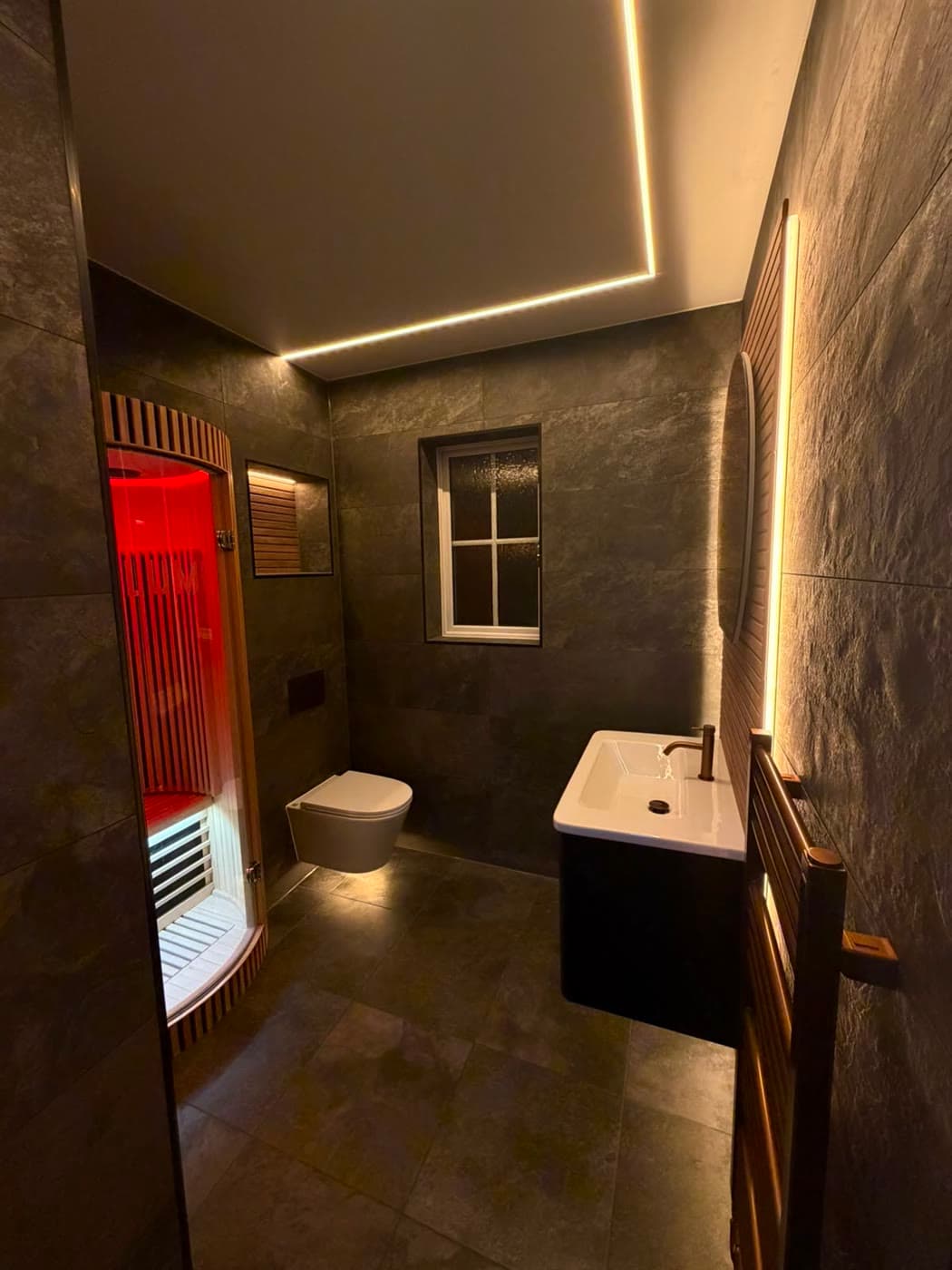 Slate tiled bathroom with a sauna cabin and slatted timber panelling, fitted by Caro Bathrooms