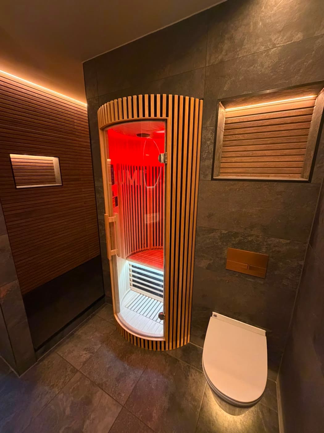 Slate tiled bathroom with a sauna cabin and slatted timber panelling, fitted by Caro Bathrooms