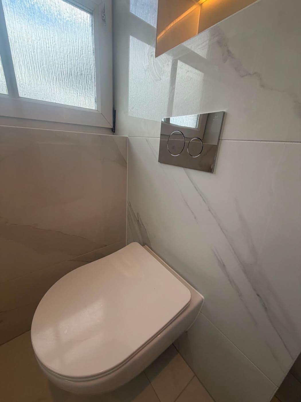 Marble tiled bathroom with a twin vanity and backlit mirrors, fitted by Caro Bathrooms