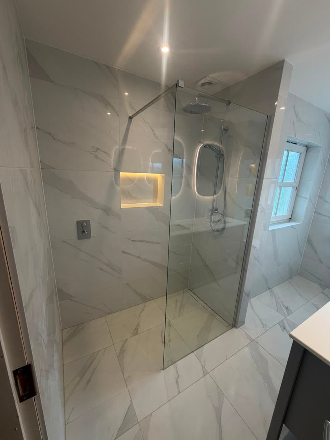 Stone tiled bathroom with brushed brass fittings and a walk-in shower, fitted by Caro Bathrooms