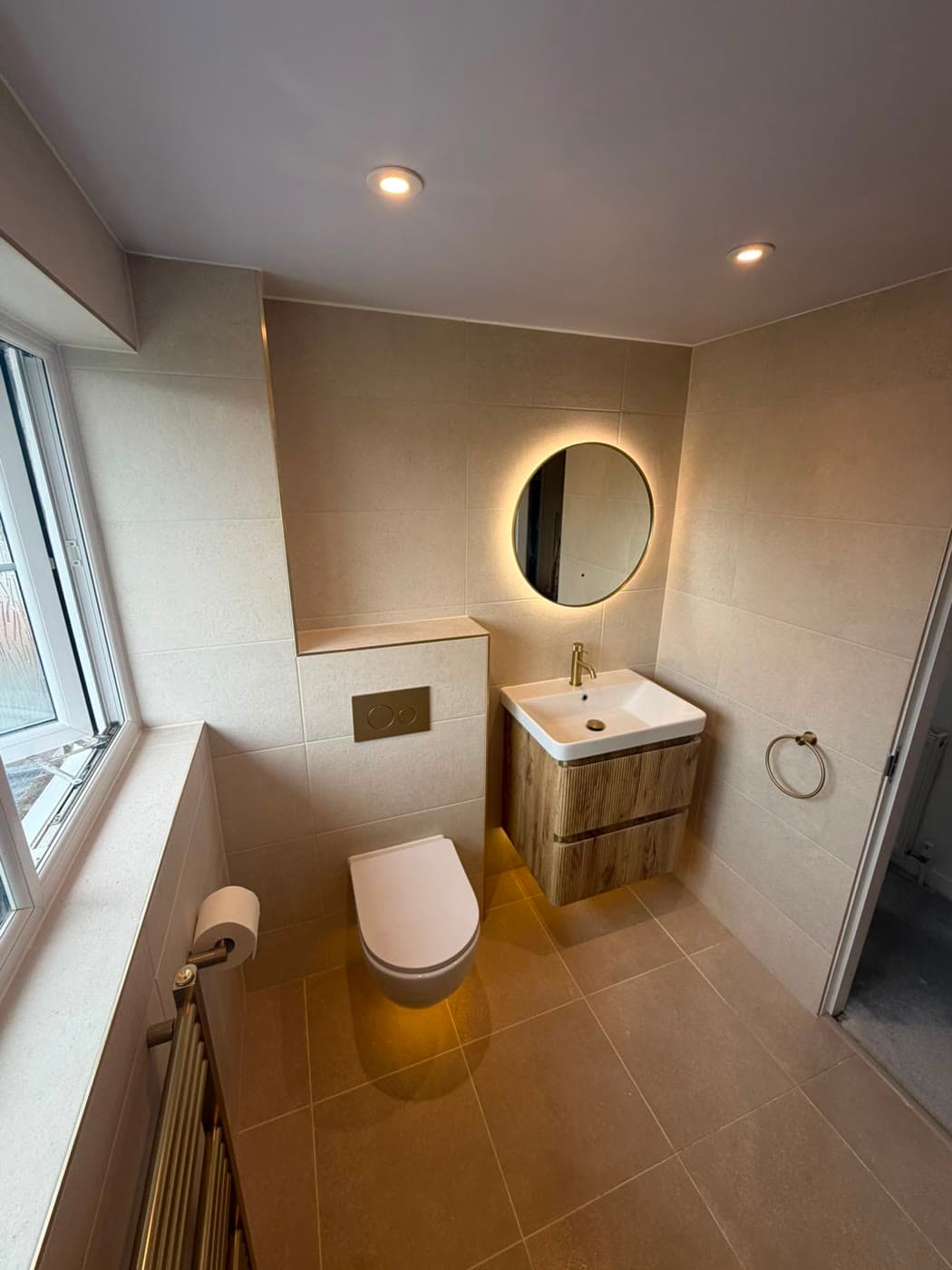 Stone tiled bathroom with brushed brass fittings and a walk-in shower, fitted by Caro Bathrooms