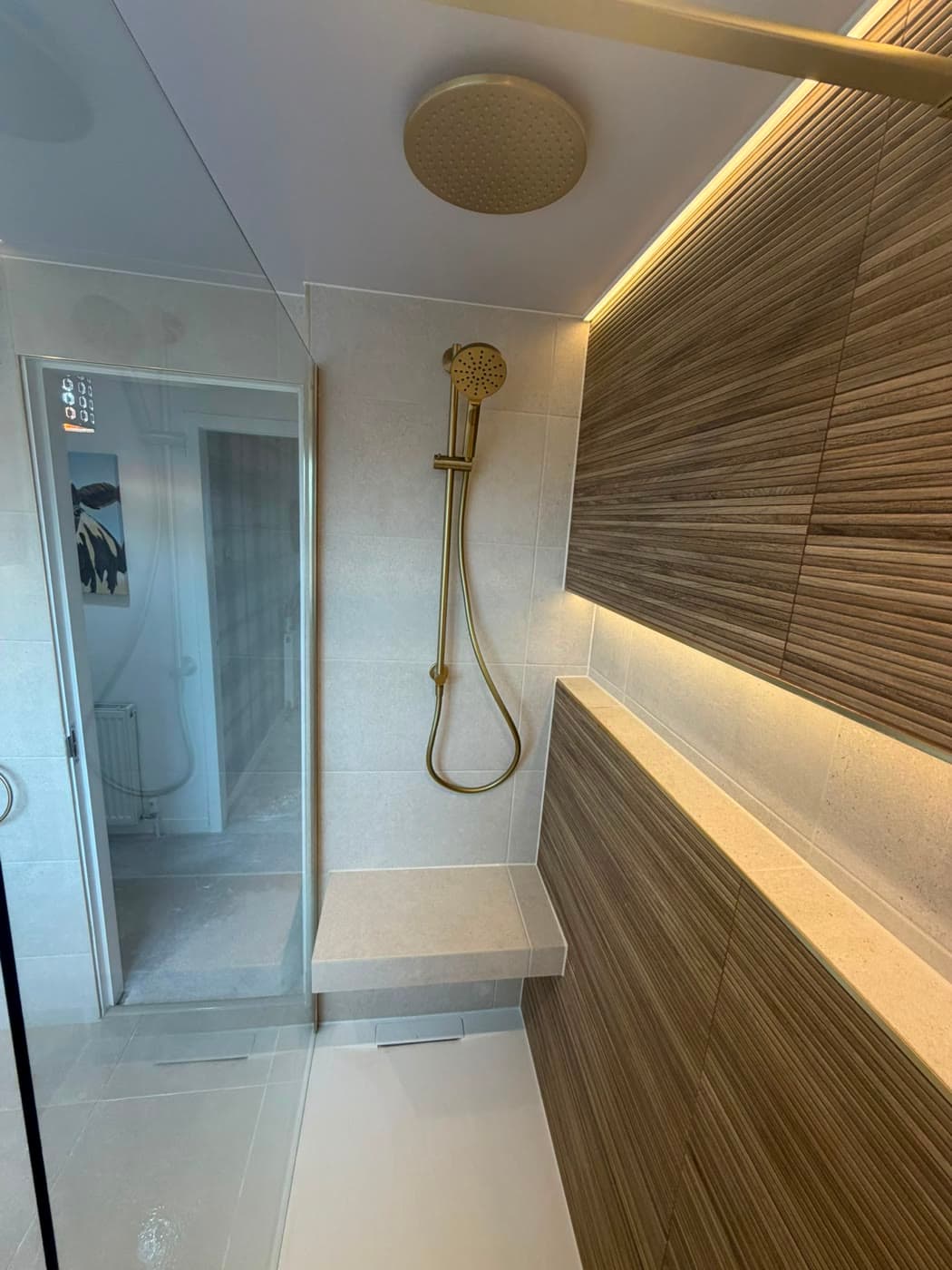 Stone tiled bathroom with brushed brass fittings and a walk-in shower, fitted by Caro Bathrooms
