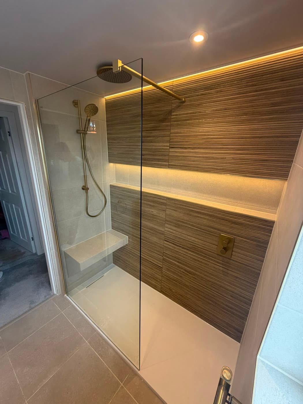 Stone tiled bathroom with brushed brass fittings and a walk-in shower, fitted by Caro Bathrooms