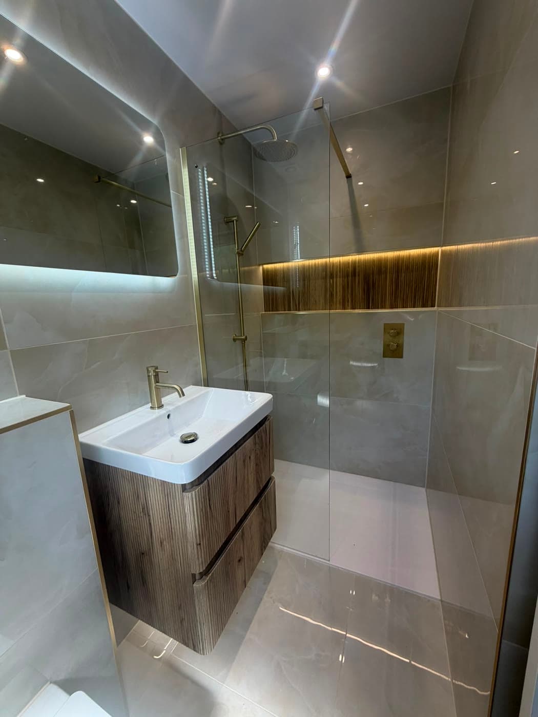 Bathroom with a wall-hung vanity, walk-in shower and a backlit niche, fitted by Caro Bathrooms