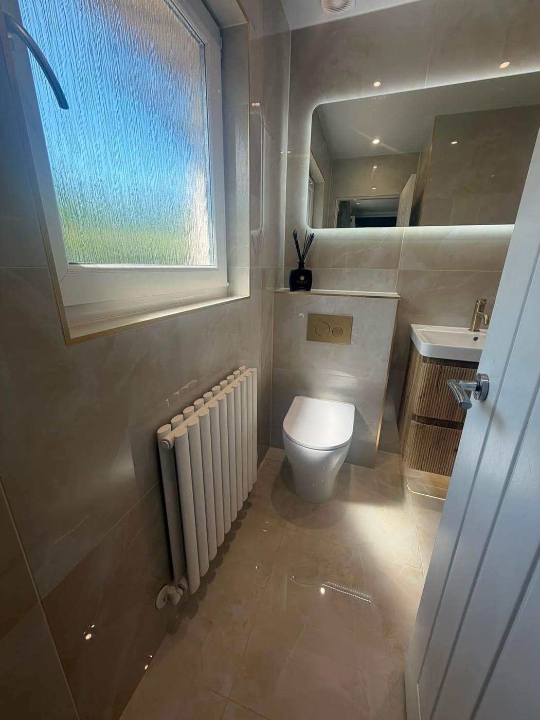Bathroom with a wall-hung vanity, walk-in shower and a backlit niche, fitted by Caro Bathrooms