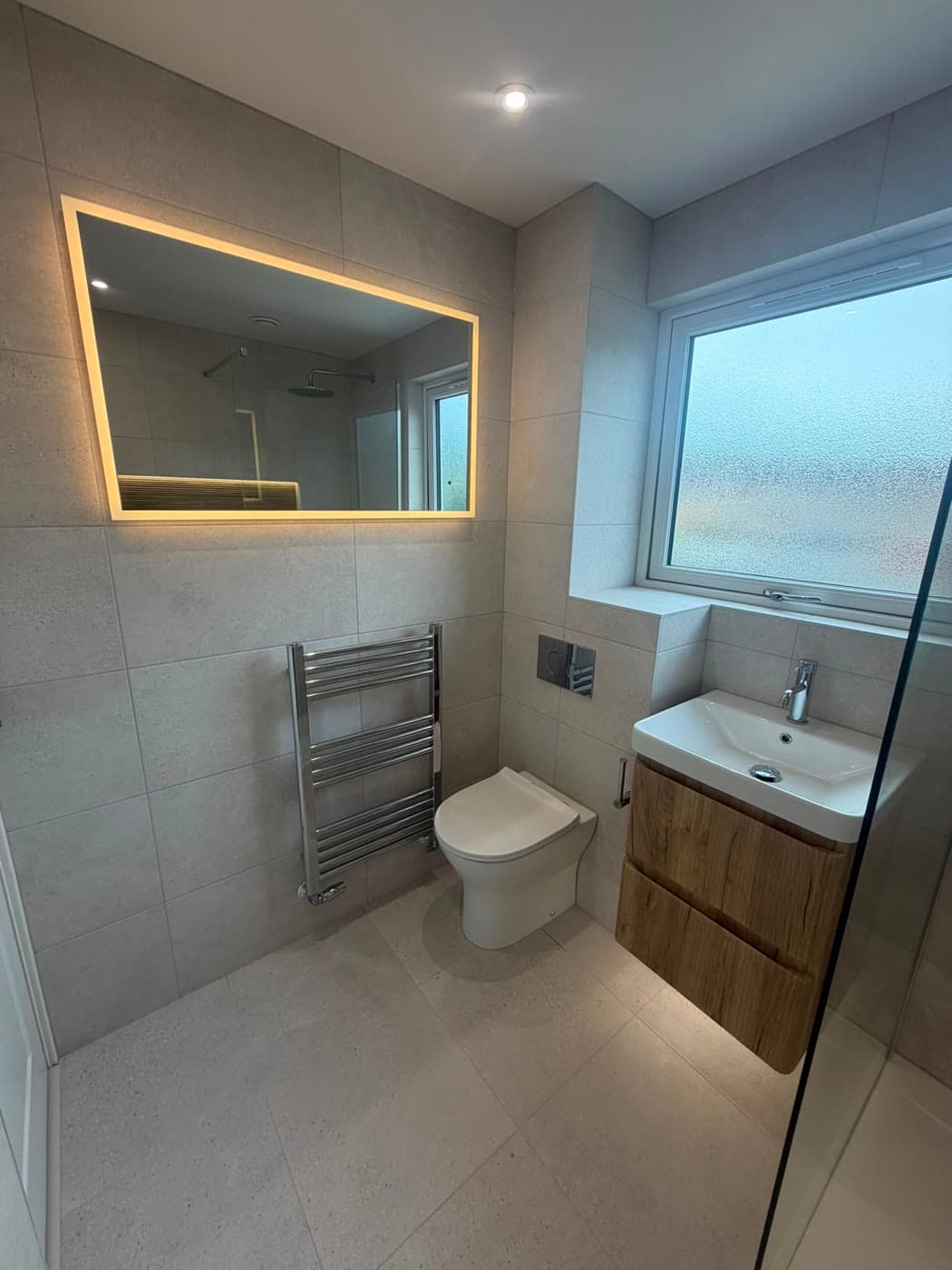 Bathroom with a wall-hung vanity, walk-in shower and a backlit niche, fitted by Caro Bathrooms