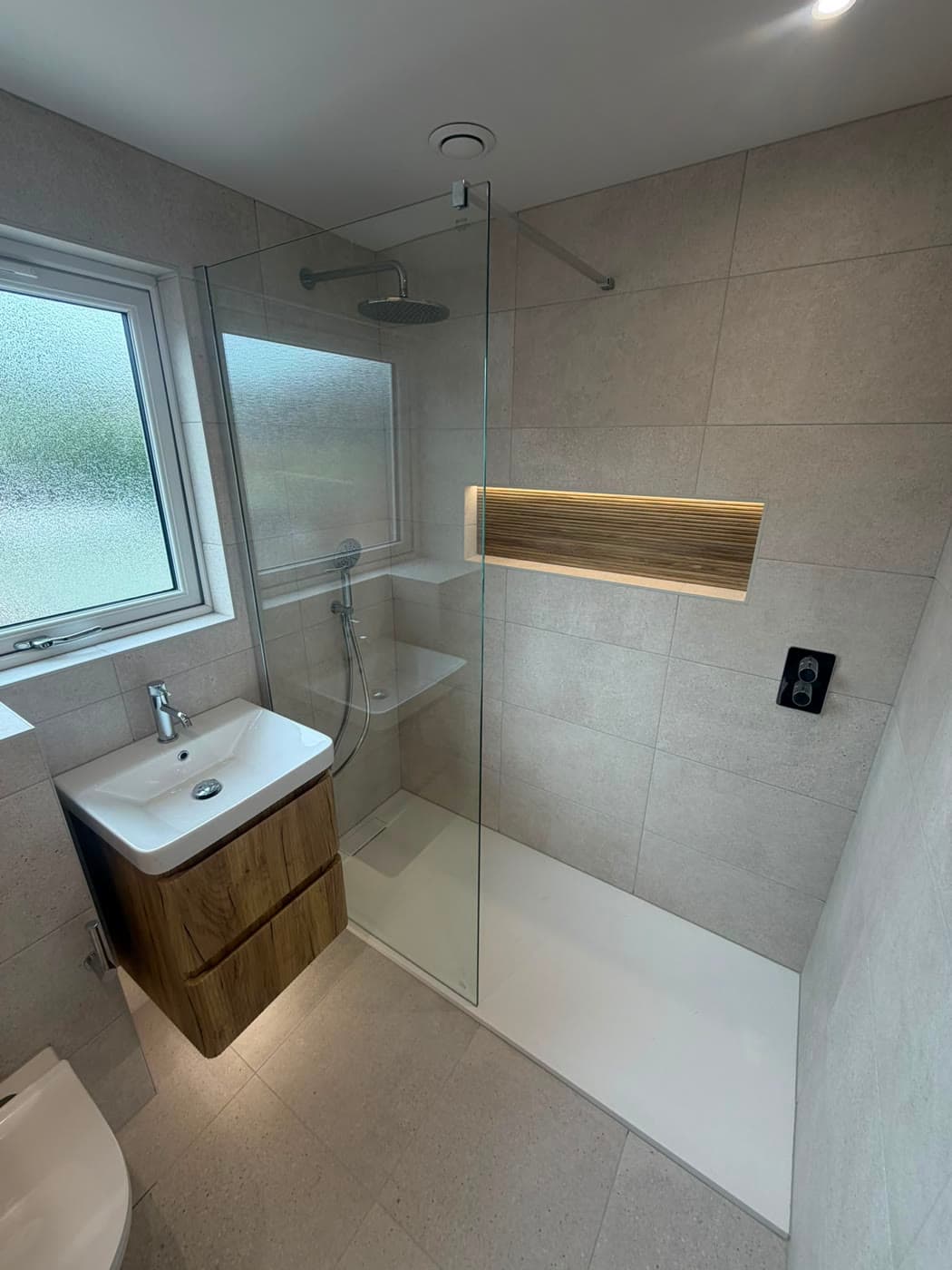Bathroom with a wall-hung vanity, walk-in shower and a backlit niche, fitted by Caro Bathrooms