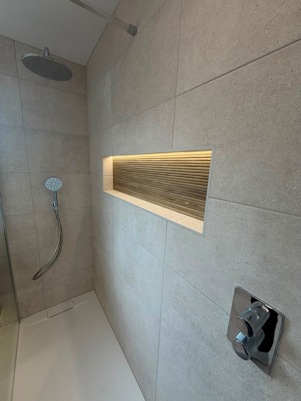 Bathroom with a wall-hung vanity, walk-in shower and a backlit niche, fitted by Caro Bathrooms