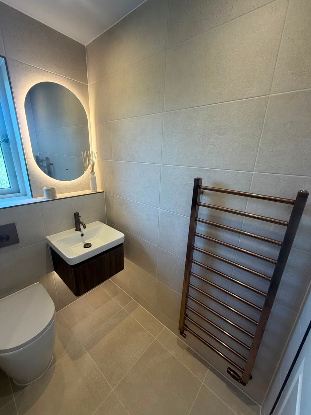 Bathroom with a timber feature wall, backlit shelving and a fitted bath, fitted by Caro Bathrooms